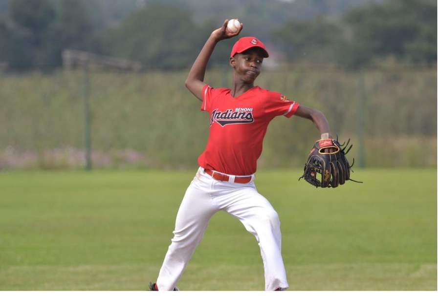 Tinashe rounding third base past his coach
